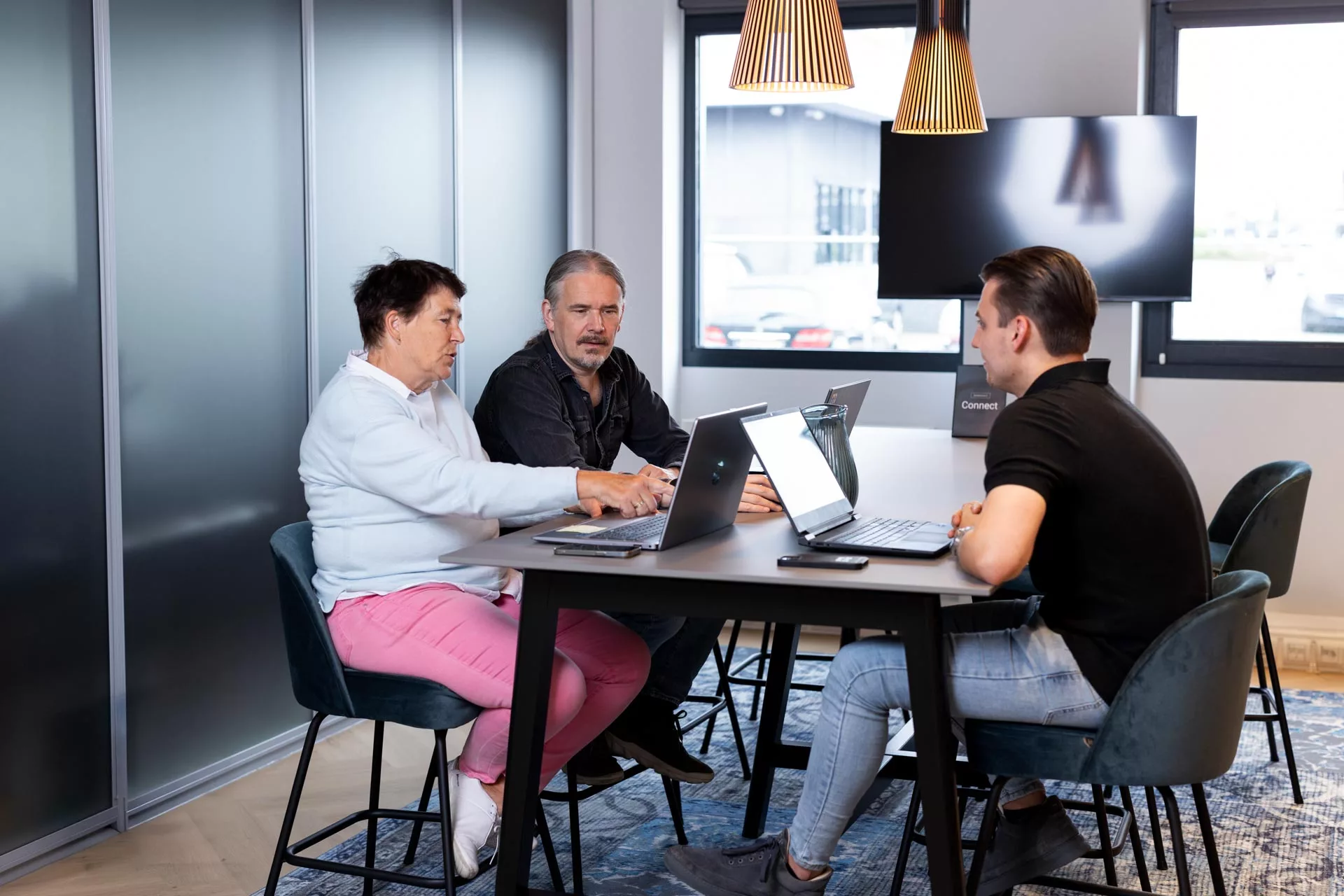 Irma Roetenberg wijst tijdens overleg over Dynamics 365, samen met Dyon Grob en Richard Ludwig bij Msquad